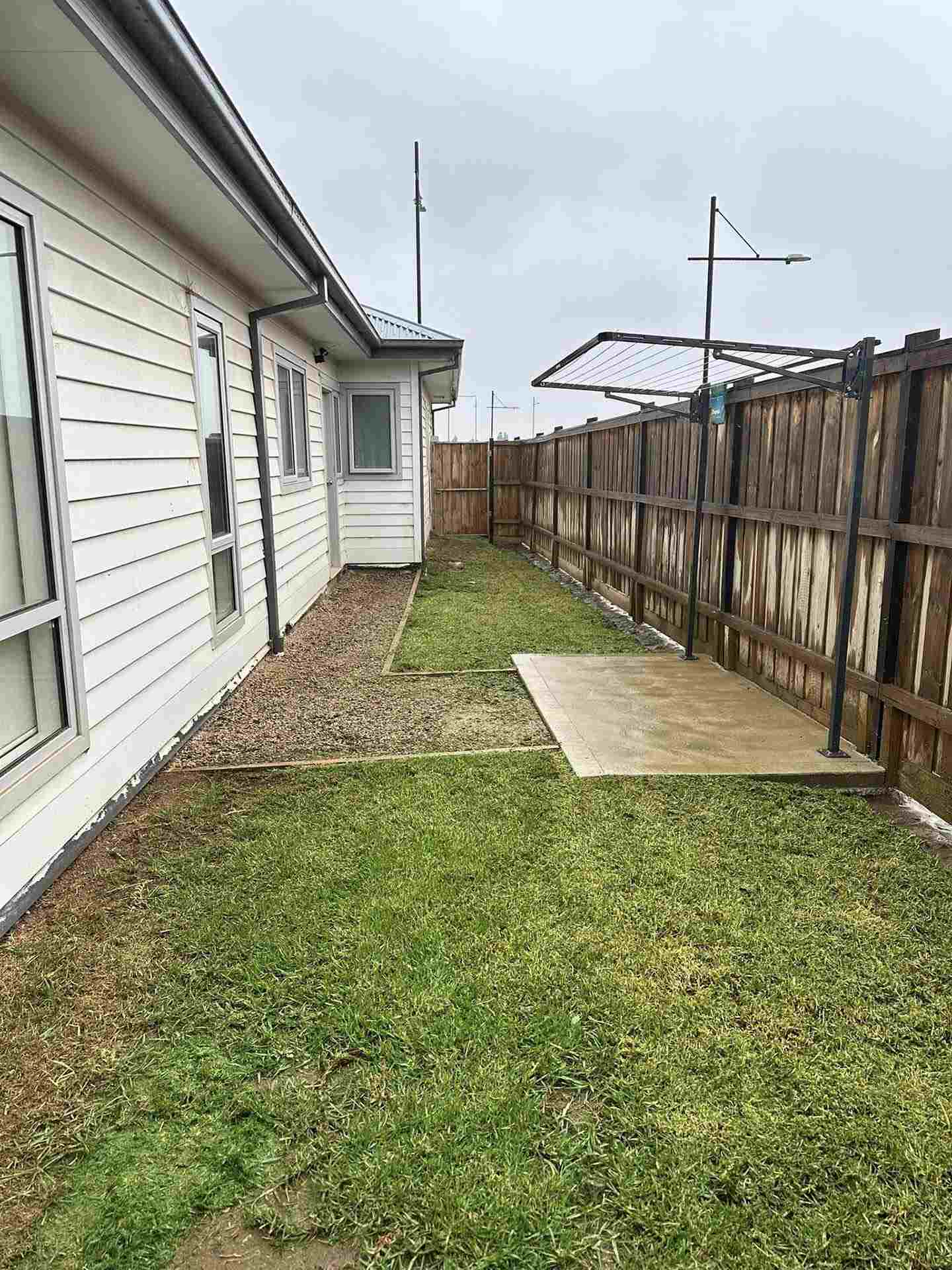 After: mown side yard lawn with a tidy gravel strip along the house